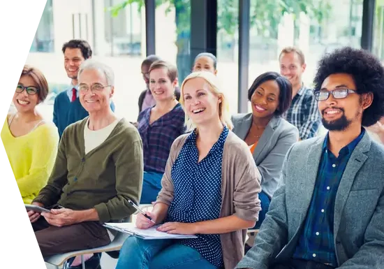 Multiculture audience sitting in presentation looking up at presenter who is not shown. 